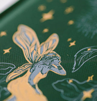 Closeup of the blue and gold fairy on a dark green notebook hardcover
