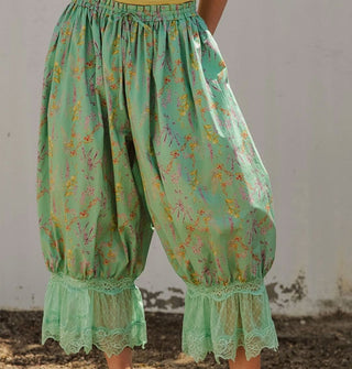 Model wears a pair of green floral print pantaloons with lace trim and an elastic tie waist