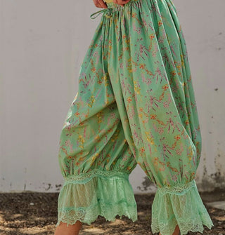 Model wears a pair of green floral print pantaloons with lace trim and an elastic tie waist
