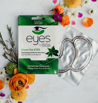 ToGoSpa Eyes Green Tea mask pack with foil pack contents removed, both flanked by colorful flowers