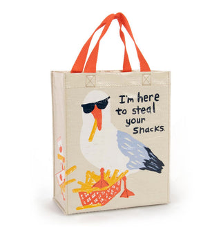Beige tote bag with orange handles features a large illustration of a seagull wearing sunglasses with its foot on a container of French fries, one of which is in its beak