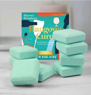 Square teal Hangover Cure Shower Steamers are stacked in front of their box packaging