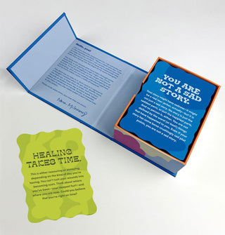 Opened box and one pulled card from the Happyish Oracle Deck; featured are "You are not a sad story" and "Healing takes time" cards