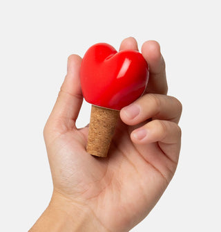 Model's hand holds a red ceramic and cork heart-shaped bottle stopper