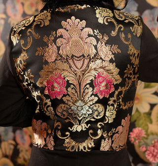 Closeup of embroidered metallic floral back panel on a fitted black jacket