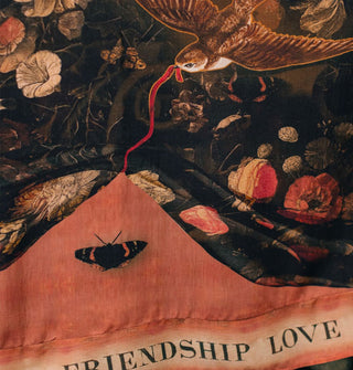 Closeup of fabric design featuring a swallow pulling a red ribbon in its beak that lifts a floral print tapestry to reveal a butterfly underneath above the words "Friendship" and "Love"