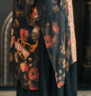 Bottom of a dark floral print robe with contrasting border features a side slit