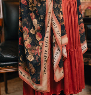 Model wears a black robe with floral print and contrasting border that says, "Friendship, Love & Truth"