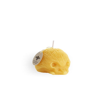 Small sculpted beeswax hedgehog candle with round tag attached to wick with string