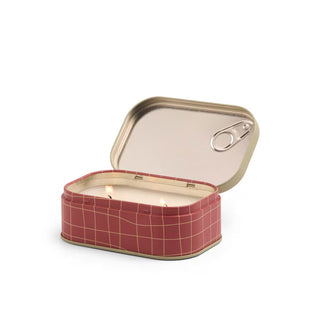 Opened tin candle with red and gold grid-patterned base and two lit wicks inside