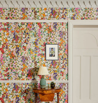 Dense, colorful floral print wallpaper in a room with white door and trim