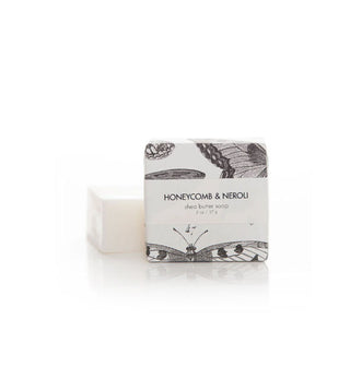 Two 2-ounce bars of Honeycomb & Neroli Shea Butter Soap, one wrapped in black and white butterfly print paper and the other unwrapped beside and slightly behind the other