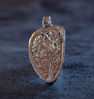 Back of pendant featuring ornate silver engraving