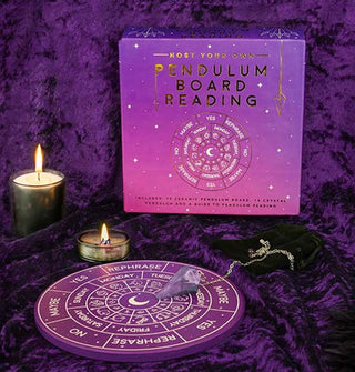 Purple Host Your Own Pendulum Board Reading box, board, and crystal-tipped chain pendulum are staged with two burning candles on a crushed purple velvet backdrop