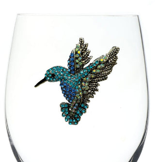 Blue- and green-jeweled hummingbird design with etched wing tips is affixed to the side of a clear wine glass