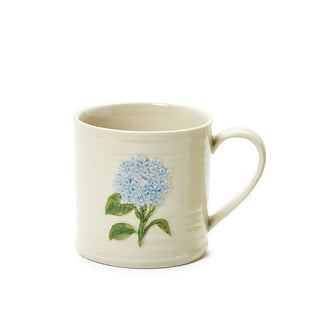 Cream-colored stoneware mug features a hand-painted embossed blue hydrangea flower design with green stem with leaves