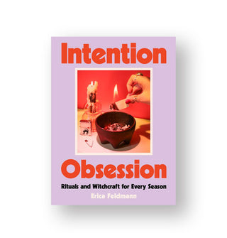 Purple cover of Intention Obsession: Rituals and Witchcraft for Every Season by Erica Feldman features a central red-dominated image of a model's hand burning wood over a mortar dish and large red title lettering 