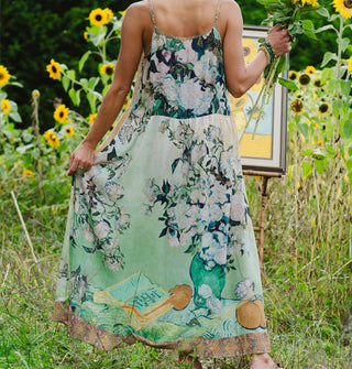Model wears a slip dress patterned with works of Vincent Van Gogh against a sunflower field backdrop