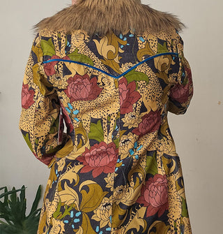 Back of a jacket with fur collar features print of cheetahs and flowers and blue velvet piping accent at the yoke