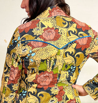 Back of a collared jacket featuring print of cheetahs and flowers and blue velvet piping accent at the yoke