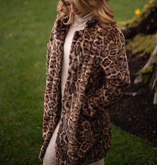 Model looking down wears a jaguar print faux fur coat with collar