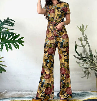 Model wears a jumpsuit with flared legs and zipper front that features a pattern of cheetahs and flowers