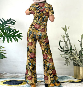 Model facing away from the camera wears a jumpsuit with flared legs and Western-style accents that features a pattern of cheetahs and flowers