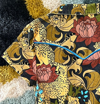 Closeup of the blue velvet piping detail on the yoke of a garment with a print of cheetahs and flowers