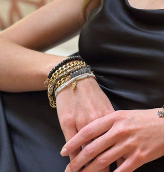 Model wears an assortment of gemstone bead and brass bracelets