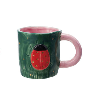 Rustic painted green ceramic mug with pink handle and interior features a red and black ladybug design with small gold stamped stars for spots