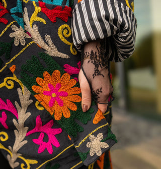 Closeup of the cuffs on a colorfully embroidered black jacket with striped lining