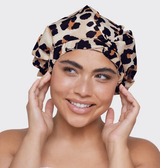 Smiling model adjusts the sides of a leopard print tuban-style shower cap