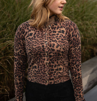 Model wears a leopard print button-down cardigan in front of tall grass and low stone wall