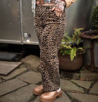Model poses with hand in the pocket of leopard print pants