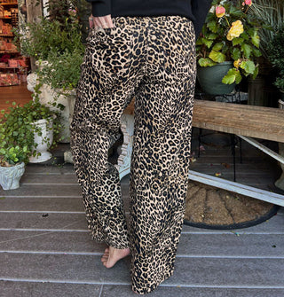 Model wears a pair of leopard print pants on a decorative porch deck