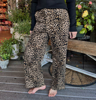 Model wears a pair of leopard print pants on a decorative porch deck