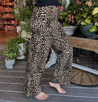 Model wears a pair of leopard print pants on a decorative porch deck