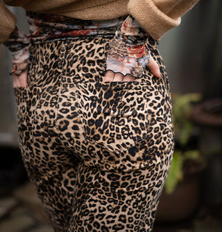 Model poses with hands in the back pockets of leopard print pants