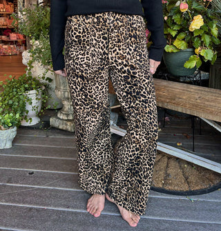 Model wears a pair of leopard print pants on a decorative porch deck