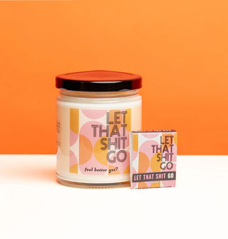 Candle jar and coordinating matchbook with orange and purple geometric design both say, "Let that shit go" in black lettering