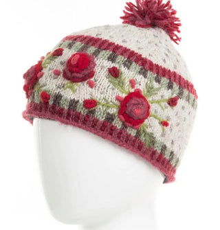 White wool beanie with textural pink, red, and green floral embroidery, geometric border designs, and a two-tone purple pom pom on top