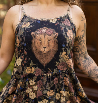 Model wears a sleeveless dress with floral patterning around a lion's head on the bodice