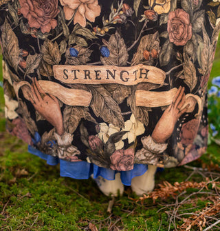 Bottom of a long robe features design of two hands holding either end of a banner that reads, "Strength"