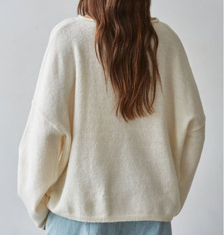 Model facing away from the camera wears a white sweater