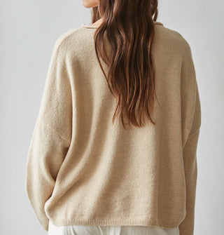 Model facing away from the camera wears a tan-colored sweater