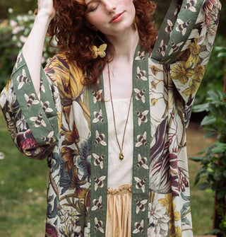 Model standing in a garden wears a robe with floral design contrasted by bumblebee print edges