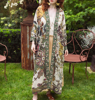 Model standing in a garden wears a long robe with floral design contrasted by bumblebee print edges