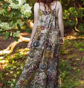 Model in a forest setting wears a lushly floral patterned slip dress