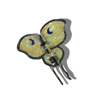 Green and gold hair clip designed to resemble a luna moth features crescent moon accents and a dark border