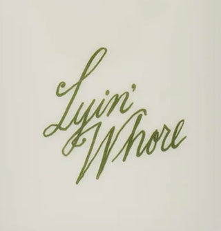 Closeup of green "Lyin' Whore" script lettering on white ceramic